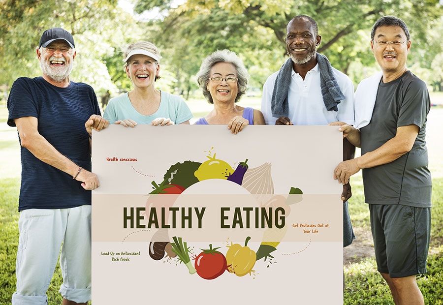 Group of smiling seniors holding a sign that reads "Healthy Eating"